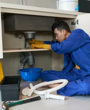 Plumber cleaning residential drain pipe using auger machine